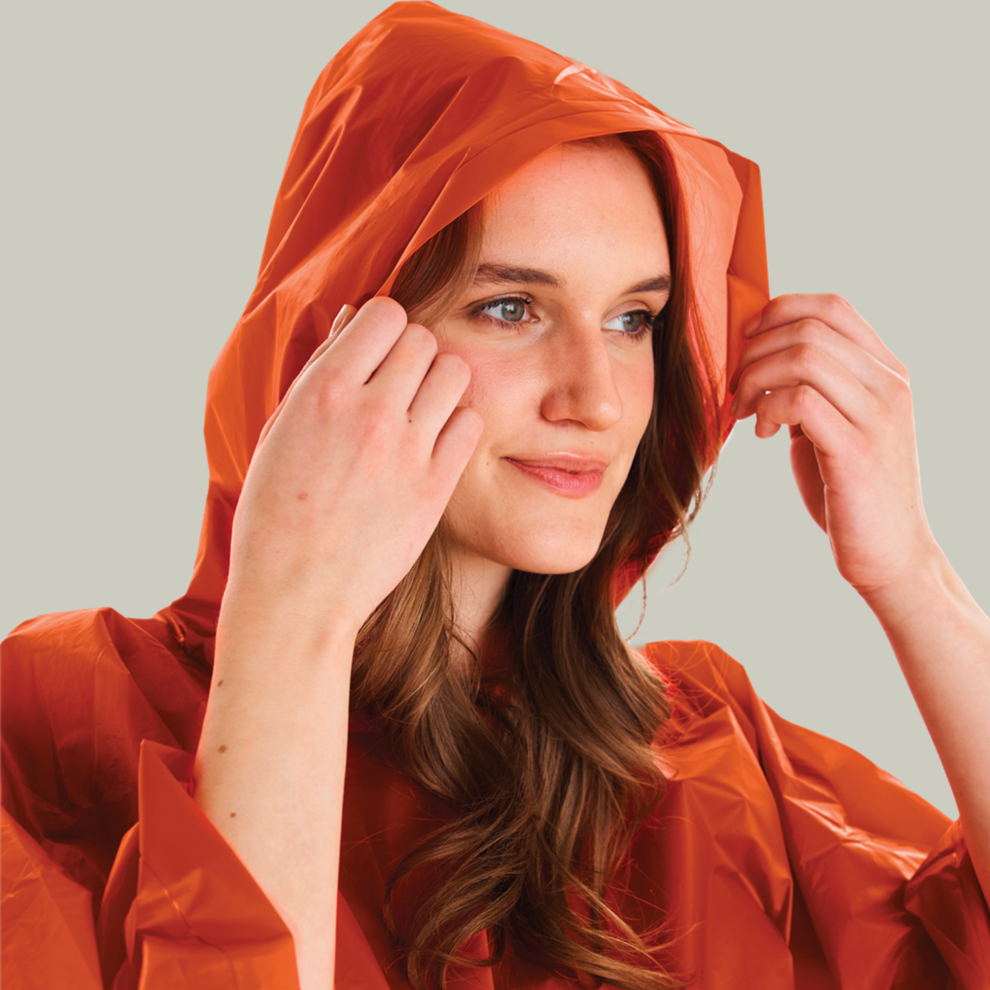 Woman wearing an orange raincoat against a plain background