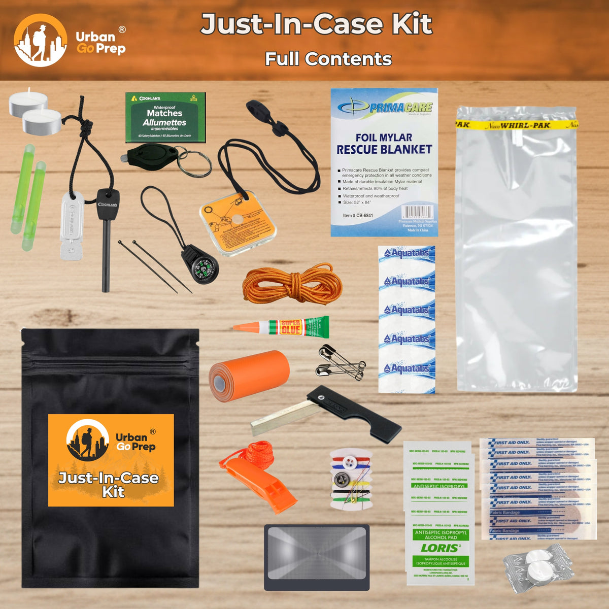 Just-In-Case Kit full contents laid out on a light wood background, including an orange Urban do Prep branded pouch, first aid items, a rescue blanket, plastic bags, matches, a whistle, compass, tape, safety pins, and other emergency preparedness supplies.