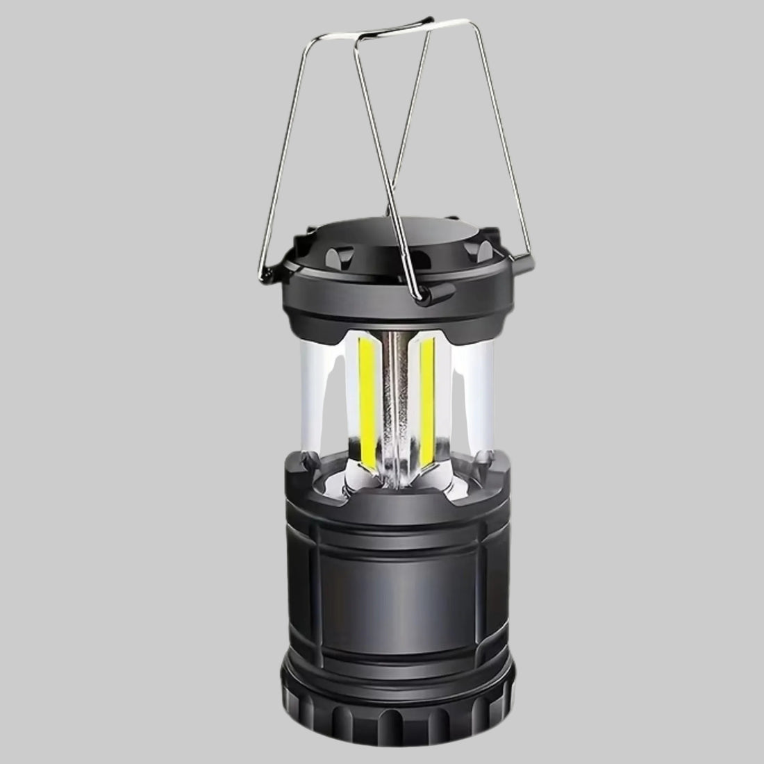 A portable camping lantern with a black body, clear glass panels, and a silver metal handle, shown against a solid light gray background.